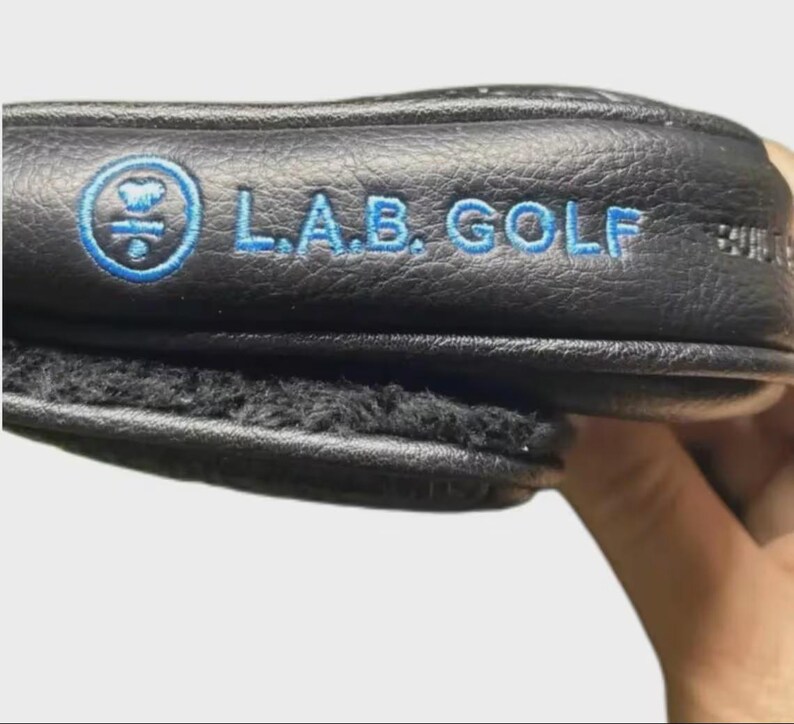 以下が含まれることがあります： 黒い持ち手と「But First, Coffee」のテキストが黒い太字でプリントされた白いセラミックマグ。マグカップはぼやけた背景に置かれており、居心地の良い環境を示唆しています。