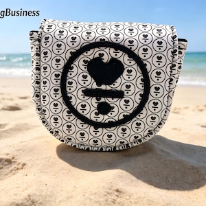 Könnte beinhalten: Eine Golfschlägerhaube mit weißem und schwarzem Muster und einem Herzdesign. Die Haube liegt an einem Sandstrand mit dem Meer im Hintergrund. Der Text "JinPengBusiness" ist oben links zu sehen.