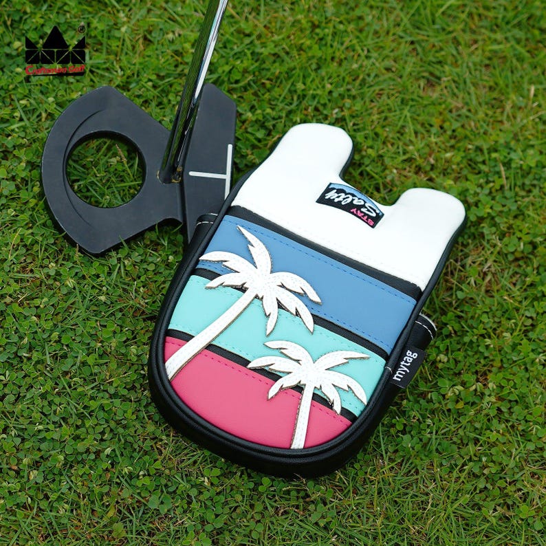 K&ouml;nnte beinhalten: Eine Golf-Putter-Kopfbedeckung mit tropischem Design mit Palmen und dem Text "Stay Salty". Die H&uuml;lle hat einen schwarzen Rand, und das Design umfasst blaue, rosa und wei&szlig;e Streifen. Der Putter ist schwarz.