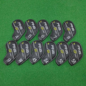Puede incluir: Un conjunto de fundas negras para palos de golf con el logotipo "PING G430" en amarillo y blanco. Cada funda está numerada del 4 al 9, con una "W", y 45, 50, 54 y 58. Dispuestas sobre una superficie verde.