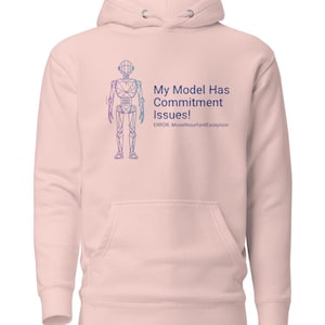 Może przedstawiać: Jasnoróżowa bluza z kapturem z przednią kieszenią i kapturem ze sznurkiem. Bluza z kapturem przedstawia niebiesko-fioletowy rysunek robota i tekst "My Model Has Commitment Issues!" z komunikatem o błędzie.