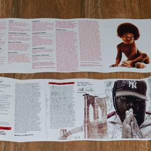 May include: Folded album insert featuring lyrics and images. The top section displays lyrics in red text. The bottom section shows a portrait of a person wearing a baseball cap and a baby image.