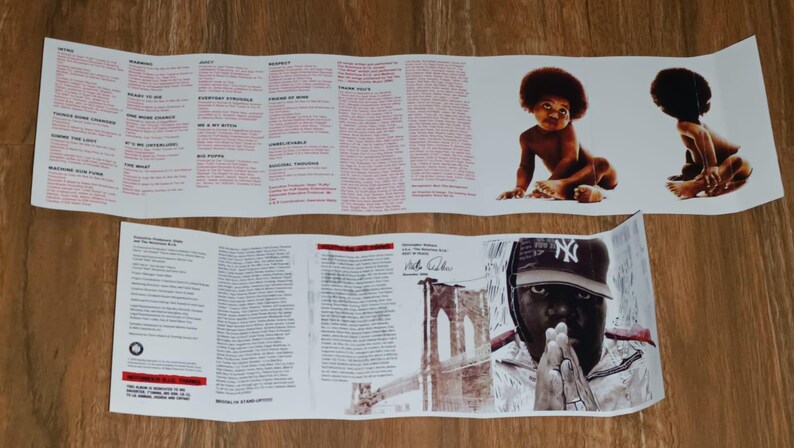 May include: Folded album insert featuring lyrics and images. The top section displays lyrics in red text. The bottom section shows a portrait of a person wearing a baseball cap and a baby image.