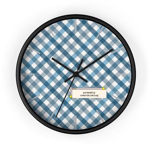 May include: Round wall clock with a black frame and a blue and white gingham pattern face. The clock hands are black. The text "probably overthinking" is displayed in a small window on the clock face.
