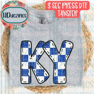 May include: A heather gray t-shirt featuring a large graphic of the letters KY in a blue and white checkered pattern with a stitched outline effect. The text 3 SEC PRESS DTF TANSFER is visible at the top, and a circular logo reads HDdezines.