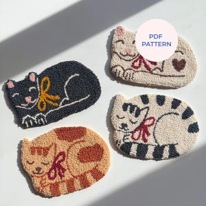 Puede incluir: Cuatro posavasos hechos a mano con forma de gato en varios colores. Uno es negro con un lazo amarillo, otro es beige con un lazo rojo y un corazón, un tercero es naranja y marrón, y el último es blanco con rayas negras y un lazo rojo. El texto "PDF PATTERN" es visible.