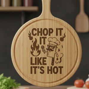 以下が含まれることがあります： ハンドル付きの丸い木製まな板。"CHOP IT LIKE IT'S HOT"の刻印と、サングラスと口ひげをした漫画のシェフが特徴です。 まな板の端には円形の溝があります。
