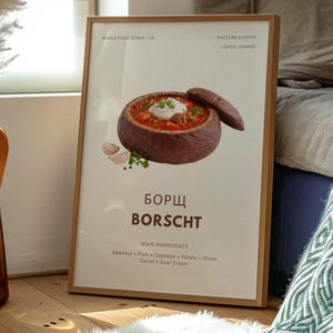 Peut inclure: Une affiche encadrée représentant du bortsch, une soupe traditionnelle d'Europe de l'Est, avec une cuillerée de crème sure. L'affiche comprend les mots "Borscht" et "Ingrédients principaux" avec une liste d'ingrédients. Le cadre est en bois.