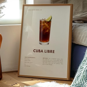 Puede incluir: Impresión enmarcada de un cóctel Cuba Libre, parte de la serie World Drink. La imagen muestra un vaso alto lleno de hielo, un líquido marrón oscuro y una rodaja de lima. La impresión incluye los ingredientes y el método.