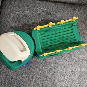 Puede incluir: Un barco de juguete de pl&aacute;stico verde y amarillo con una tapa blanca y verde. El barco tiene una base verde con detalles amarillos y una tapa blanca con asa. Dise&ntilde;ado para el juego infantil.
