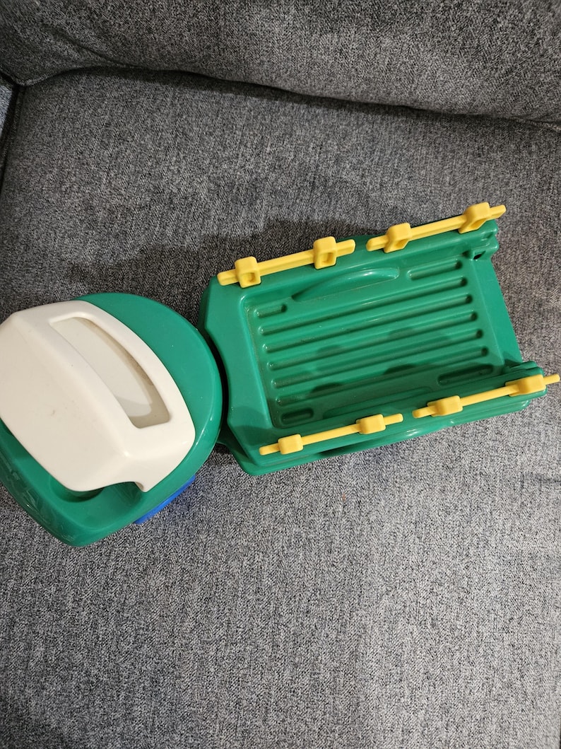 Puede incluir: Un barco de juguete de pl&aacute;stico verde y amarillo con una tapa blanca y verde. El barco tiene una base verde con detalles amarillos y una tapa blanca con asa. Dise&ntilde;ado para el juego infantil.