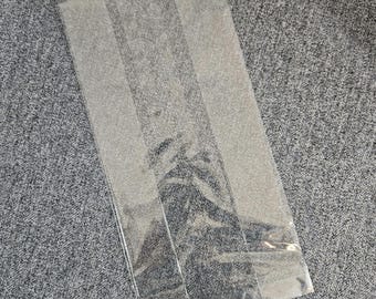 May include: Clear plastic bags with a textured surface. The bags are stacked on top of each other.