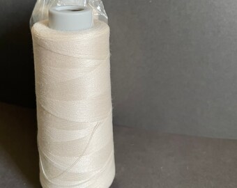 May include: A spool of white thread on a plastic bobbin.