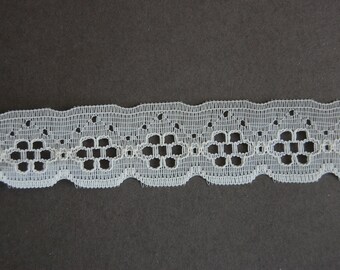 May include: White lace trim with a delicate floral pattern. The trim has a scalloped edge and is perfect for adding a touch of elegance to any project.