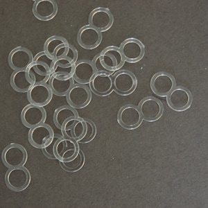 May include: A pile of clear plastic rings, some are connected in pairs to form a figure eight shape.