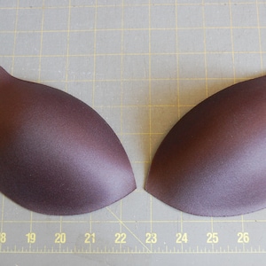 Op de afbeelding: Twee bruine stoffen bh-bekers, waarschijnlijk voor naai- of knutselprojecten.