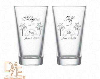 May include: Two clear glass pint glasses with black text and graphics. The left glass says "Megan Mrs June 2, 2023" and the right glass says "Jeff Mr June 2, 2023". Both glasses have a palm tree and sunset graphic.