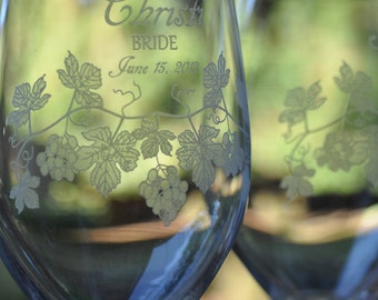May include: Two clear glass wine glasses with etched grapevines and the text "Christ Bride June 15, 2019".