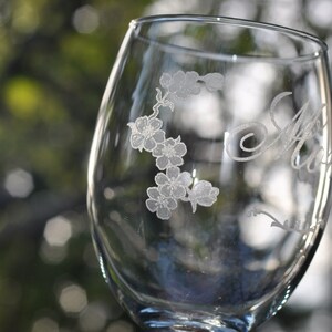 May include: A clear glass wine glass with an etched design of flowers and the word "Aunt" on the side.