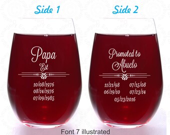 May include: Two wine glasses with red wine. The glass on the left has the text "Papa Est" and dates. The glass on the right has the text "Promoted to Abuelo" and dates.