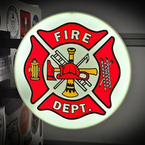 May include: A circular, illuminated wall-mounted sign featuring a red Maltese cross emblem with the text FIRE DEPT. The center displays a yellow fire hydrant, a ladder, a fire axe, and a red fire helmet. The sign is mounted on a black bracket.