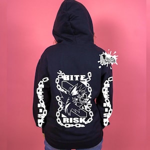 May include: Dark blue hooded sweatshirt with white graphic text and design. The back features the words "BITE RISK" around a cartoon character in a chain. White text is also on the sleeves. The hoodie has a drawstring hood.