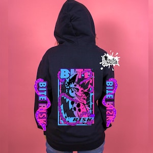 May include: Dark grey hoodie with a graphic of a cartoon animal and the words "Bite Risk". The design uses pink, blue, and purple. The sleeves have the words "Bite Risk" in a vertical design.
