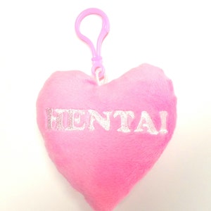 May include: Pink heart-shaped plush keychain with a white clip and the word "HENTAI" embroidered in white.