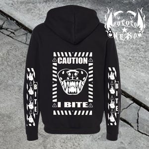 Peut inclure: Un sweat-shirt à capuche noir avec un motif blanc au dos représentant une tête de serpent, le texte CAUTION et I BITE, ainsi que des symboles de danger. Les manches présentent un motif répété de petites têtes de serpent et le mot BITE.