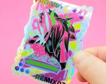 May include: A holographic sticker featuring a pink and black cartoon character with green horns and a white and green halo. The character is holding a green and blue DJ mixer. The sticker has a rainbow iridescent finish and the text "PRG-VO1" and "REMIX02" on it.