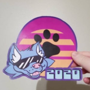 May include: A blue cartoon wolf wearing sunglasses with a purple paw print and the year 2020 on a pink and orange background.
