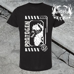 May include: A black short-sleeved t-shirt featuring a white graphic print of a stylized robotic creature head. The design includes the text PROTOGEN, the number 51, and geometric border elements with warning symbols, all rendered in a distressed white ink.