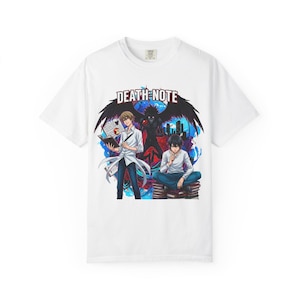 May include: White t-shirt featuring a graphic from the anime series Death Note. The design includes the series title, two characters, and a dark figure with wings, set against a blue and purple background.