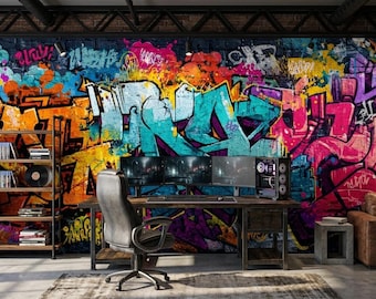 May include: A vibrant graffiti mural dominates the background, featuring bold lettering and colorful abstract designs in shades of orange, blue, and purple. A wooden desk with multiple computer monitors and a gaming PC sits in front of the mural.