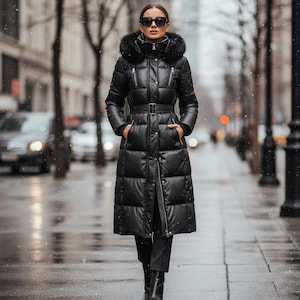 Könnte beinhalten: Ein langer, schwarzer Steppmantel mit Pelzkapuze und Taillengürtel. Der Mantel hat ein gestepptes Design und wird mit schwarzer Hose und Stiefeln getragen. Die Person trägt eine Sonnenbrille und steht auf einer Stadtstraße.
