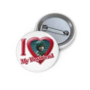 Op de afbeelding: Witte knoop met de tekst "I My Boyfriend" in het rood en een hartvormige lijst. Het hart bevat een foto van een man. Een tweede knoop is zichtbaar op de achtergrond.