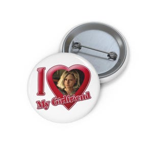 Op de afbeelding: Witte knoop met de tekst "I My Girlfriend" in het rood en een rode hartvorm met een foto van een vrouw. De knoop heeft een metalen speld aan de achterkant.