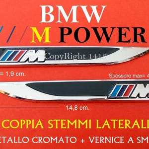 Puede incluir: Dos emblemas BMW M Power cromados y negros. Cada emblema mide 14,8 cm de largo, 1,9 cm de alto y un grosor máximo de 4,5 mm. Los emblemas presentan el logotipo BMW M en azul, rojo y blanco. El texto "BMW M POWER" se muestra arriba.