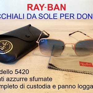 Pu&ograve; includere: Occhiali da sole Ray-Ban, modello 5420, con lenti sfumate blu. Gli occhiali hanno una montatura color oro e sono accompagnati da un astuccio nero e un panno per la pulizia. Il logo Ray-Ban &egrave; visibile sull'astuccio e sul panno.
