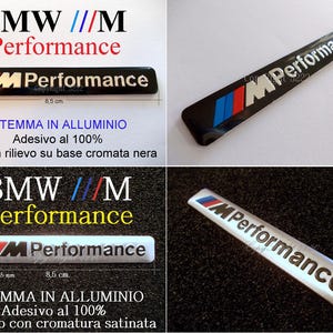 Könnte beinhalten: Schwarzes und silbernes BMW M Performance Emblem. Das Emblem hat das BMW-Logo mit blauen, roten und weißen Streifen. Der Text "M Performance" ist weiß. Das Emblem ist 8,5 cm lang und 1,2 cm breit.