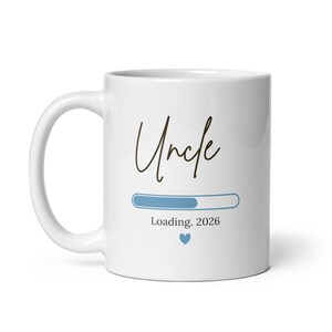 May include: White ceramic mug with the word "Uncle" in a handwritten font. Below is a blue progress bar with the text "Loading. 2026" and a blue heart. A gift for a future uncle.