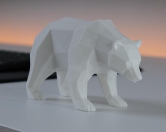 May include: A white bear figurine featuring a geometric, faceted design with sharp angles and flat surfaces. The bear is depicted in a standing, walking posture with its head slightly lowered, showcasing a clean, solid white matte finish throughout.