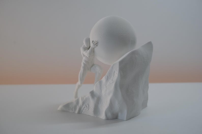 May include: A matte white sculpture depicting a stylized human figure pushing a large sphere up a jagged, rocky incline. The monochromatic piece features smooth surfaces on the figure and sphere, contrasting with the textured, uneven rock base.