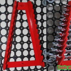 May include: Red wrench organizers mounted on a black grid. The organizers hold a set of wrenches. The text "Tools are not included" is visible in green. The organizers are designed to hold wrenches of various sizes.