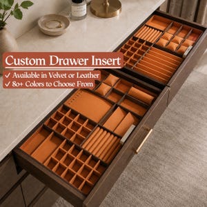 May include: A dark wood drawer organizer insert featuring multiple compartments lined in orange fabric. The interior includes square grids, rectangular sections, and padded watch cushions. Text on the image reads Custom Drawer Insert.
