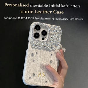 May include: White leather phone case with crystal detailing and the initials "AS". The case is designed for various iPhone models and features the text "Personalised inevitable Initial kafr letters name Leather Case".