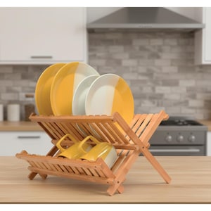 Puede incluir: Un escurreplatos de madera con platos amarillos y blancos y tazas amarillas. El estante es de madera clara y tiene un dise&ntilde;o de listones. Los platos tienen una combinaci&oacute;n de colores de dos tonos.