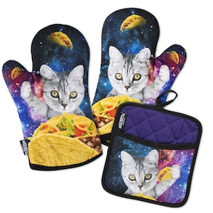 Può includere: Un paio di guanti da forno e una presina quadrata con uno sfondo a tema spaziale con nebulose e stelle. Ogni articolo mostra un gatto soriano grigio che tiene un taco, con altri taco che fluttuano nella galassia e bordi di colore nero.