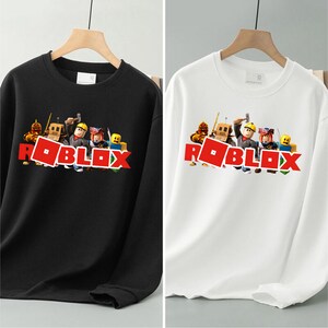 May include: Black and white sweatshirts with the Roblox logo in red. The sweatshirts have a crew neck and long sleeves. The Roblox logo is accompanied by cartoon characters.