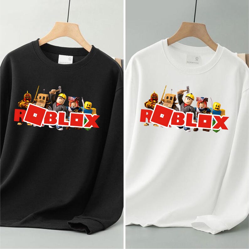 May include: Black and white sweatshirts with the Roblox logo in red. The sweatshirts have a crew neck and long sleeves. The Roblox logo is accompanied by cartoon characters.